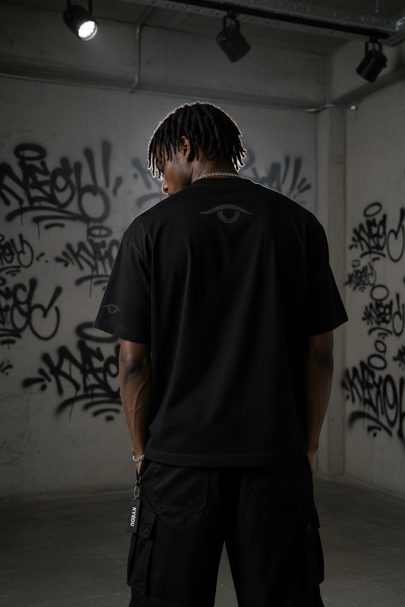 Person wearing a black t-shirt with 'KYEOU' branding in a dark setting
